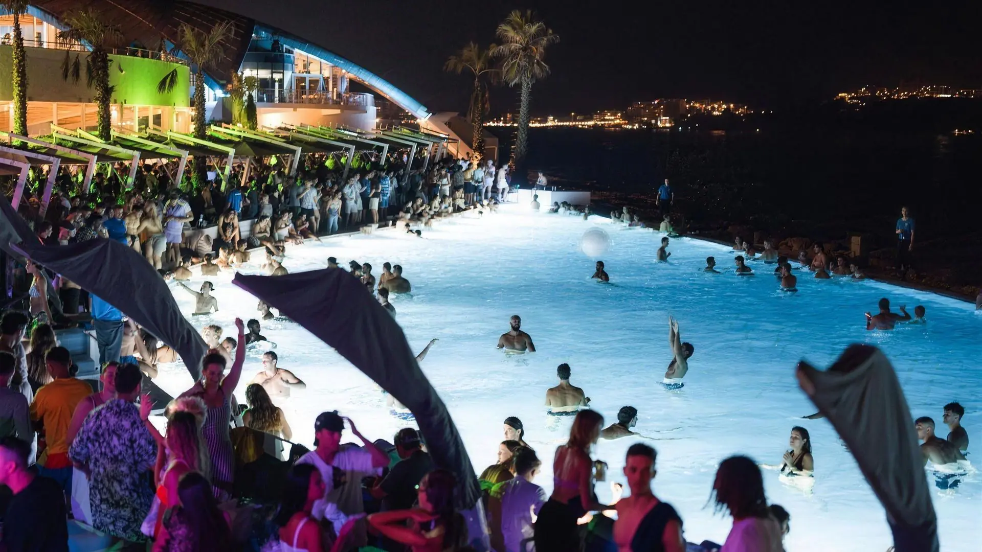 Café del Mar Malta seen from above at night, its pool lit up beside the bay